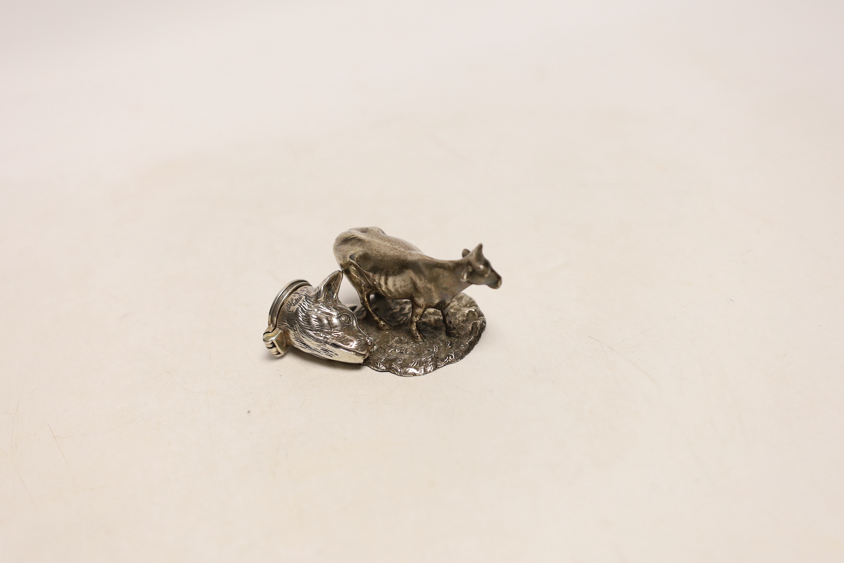 A mid Victorian silver model of a cow, on rustic circular base, Edward & John Barnard, London, circa 1860, length 55mm and a white metal small box modelled as a fox head, with hinged cover.